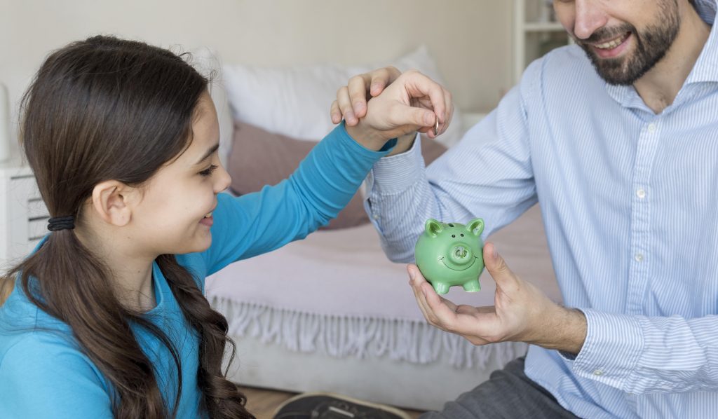 father-daughter-putting-money-piggy-bank